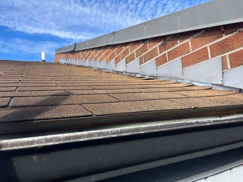 Close-up view of a professionally installed roof flashing along a brick wall, illustrating effective roof flashing installation to prevent water damage