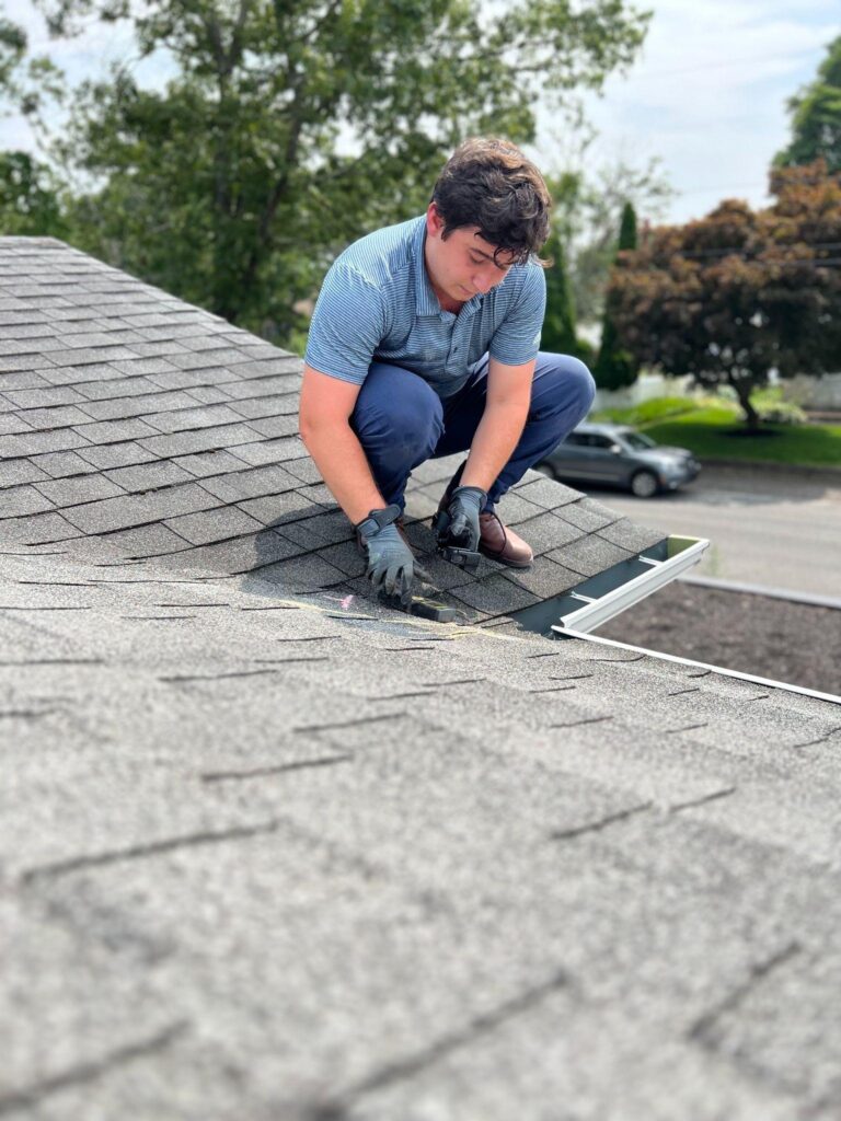 Roofing professional inspecting shingles for damage, providing a roof repair free estimate to assess necessary repairs and maintenance.