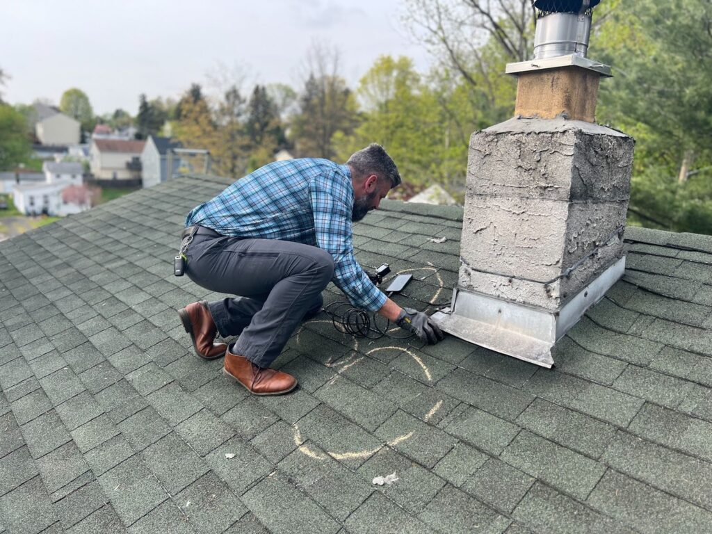 A roofing professional inspecting a chimney flashing on a residential roof, providing a free estimate for roofing repairs and maintenance.