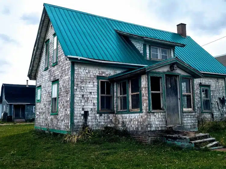 An old house with a deteriorating metal roof, demonstrating a case where emergency roofing services are needed for repairs or replacement