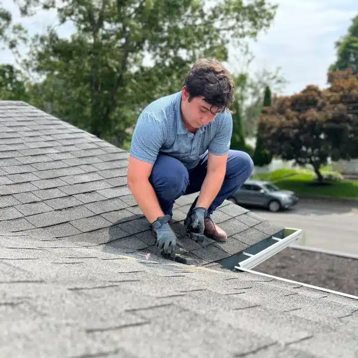 A professional roofer inspecting shingles, illustrating a critical step in determining how to know when roof was replaced through thorough examination.